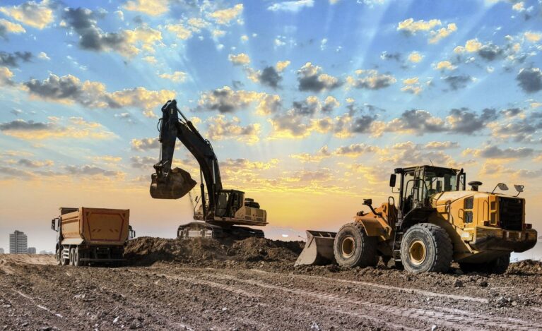 Excavators working on construction site at sunset